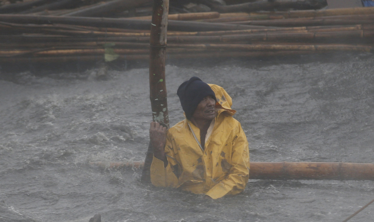 Fisherman secures his fishpen from strong winds and rain brought by Typhoon Rammasun (locally named Glenda) as it hit the coastal town of Bacoor